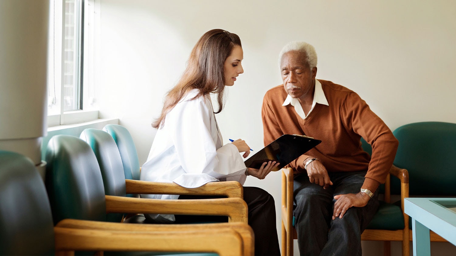 Un médico con un portapapeles discutiendo opciones con un paciente